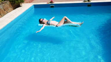 bin yıllık kız float Havuzu, Festivali, otel, plaj, yaz aylarında güneş gözlüğü üzerinde gülümseyen olay. Güneş zevk. Tatil kavramı. Mavi Hava ince genç kadının bikini Üstten Görünüm