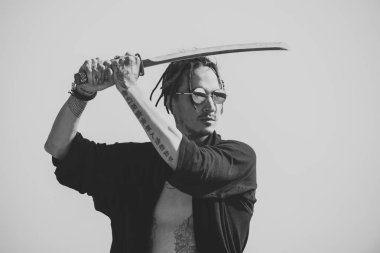 Olan dreadlocks ve açık elbiseler gösterilen savaşçı gövde dövme. Gri gökyüzü üzerinde katana kılıcı duran adamla