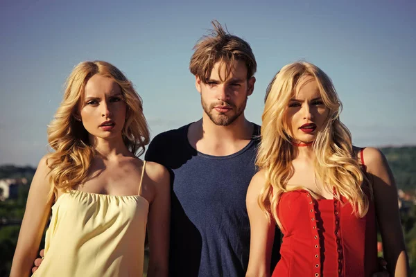 Gemelos mujeres con macho sobre fondo azul cielo . — Foto de Stock