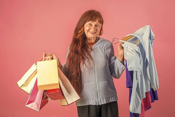 Woman with long red hair hold colorful shopping bag. Christmas and birthday. Clothes in hand of happy woman.