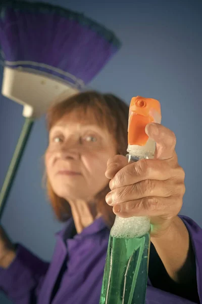 Old lady cleaner with broom on blue background. Cleanup and order services. Cleaning and purity. — Stock Photo, Image