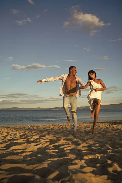 Fantasia de dois segredos. Homem e mulher de mãos dadas, casal feliz nas férias. Casal apaixonado fica na praia, na praia. Casal apaixonado andando, se divertindo, mar e horizonte de fundo. Lua-de-mel, apenas — Fotografia de Stock