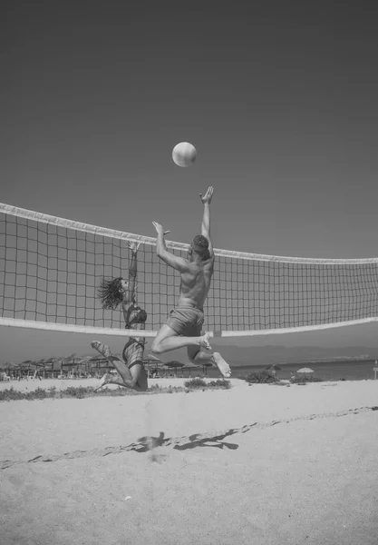 Reizvolles Paar. Das Paar hat Spaß beim Volleyball. junges sportliches aktives Paar schlägt Volleyball, spielt Spiel am Sommertag. Frau und Mann sind fit, stark, gesund und treiben Sport am Strand. Beach-Volleyball — Stockfoto