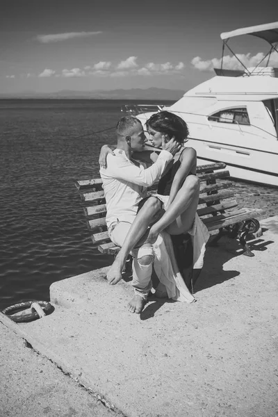 Romantic man and woman couple having intimate sex. Woman and man in fashionable clothes full of desire near luxury yacht. Couple in love on honeymoon. Honeymoon concept. Young passionate couple sit on