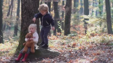Mutlu küçük çocuk, küçük kız gülerek ve oynayarak sonbaharda doğa yürüyüşünde.