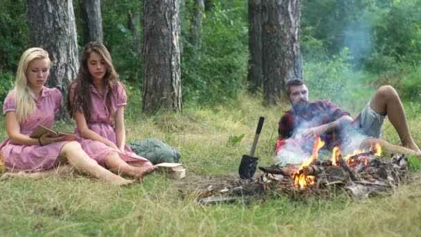 Glada vänner spelar musik och njuter av brasa i naturen. Tonåringar ha kul på skogen. Vänner som sitter i skogen i cirklar runt en lägereld. — Stockvideo