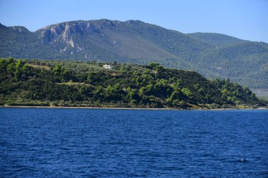Deniz ve dağ manzara mavi gökyüzü üzerinde. Güneşli yeşil ağaçlar ile yalı. Yaz tatil ve yolculuk tutkusu. Bulma veya macera ve seyahat.