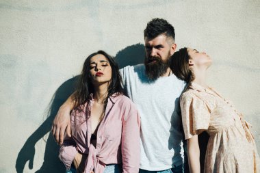 İki kadınla beyaz duvardan ayakta sakallı adam. Adam acımasız femme fatale ve masum genç kız, aşk üçgeni, ilişki sorunları kavramı arasında seçim yapma.