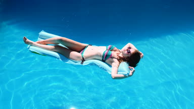 bin yıllık kız float Havuzu, Festivali, otel, plaj, yaz aylarında güneş gözlüğü üzerinde gülümseyen olay. Güneş zevk. Tatil kavramı. Mavi Hava ince genç kadının bikini Üstten Görünüm