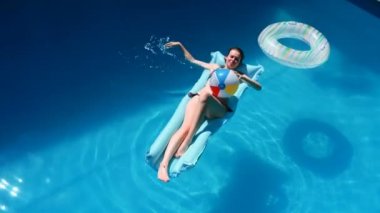 bin yıllık kız float Havuzu, Festivali, otel, plaj, yaz aylarında güneş gözlüğü üzerinde gülümseyen olay. Güneş zevk. Tatil kavramı. Mavi Hava ince genç kadının bikini Üstten Görünüm