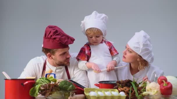 Παιδί παιχνίδι. Χαριτωμένο μικρό αγόρι και όμορφες οι γονείς του χαμογελαστός κατά το μαγείρεμα στην κουζίνα. Νεαρή οικογένεια μαγείρεμα των τροφίμων στην κουζίνα. Ευτυχισμένη οικογένεια μαγείρεμα μαζί. Ευτυχισμένη οικογένεια μικρά με τη μαμά, τον μπαμπά παιδί — Αρχείο Βίντεο