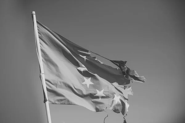 Unión Europea bandera de doce estrellas desgarrada y con nudos en el viento sobre el fondo del cielo azul. La bandera es arrancada a un lado, símbolo de problemas, decadencia, desintegración, descomposición, ruptura — Foto de Stock