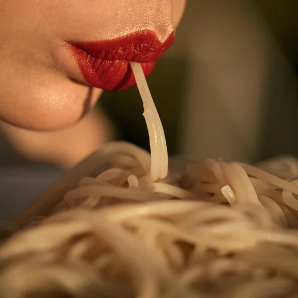 Lábios maquiagem comer macarrão ou espaguete ao ar livre, close-up. maquiagem ou moda, lábios sexy com lipstock vermelho de mulher ou menina comendo espaguete. As mulheres enfrentam cuidados com a pele. Retrato de mulheres rosto em seu advertisnent . — Fotografia de Stock