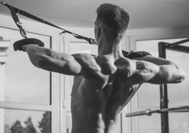 Adam çıplak gövde ve geri içinde jimnastik salonu kas eğitim, trx tadını çıkarın. Spor ve spor salonu konsept. Sporcu, atlet, kas maço mu egzersiz trx döngüler ile arka plan, pencereye yakın.