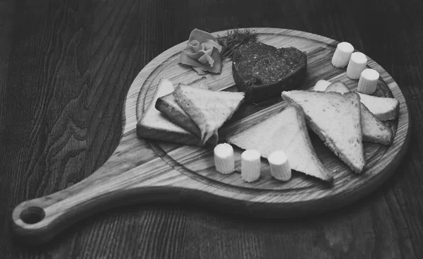 Schotel smakelijk ingericht met dille. Tatar biefstuk in vorm van hart op ronde houten plank geserveerd. Brood, toast en boter rond biefstuk aan boord. Schotel restaurantconcept — Stockfoto