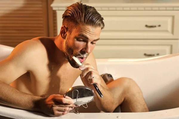 Mens läker kroppsvård. Barber man rakning skägg med vintage rakkniv i badkar — Stockfoto