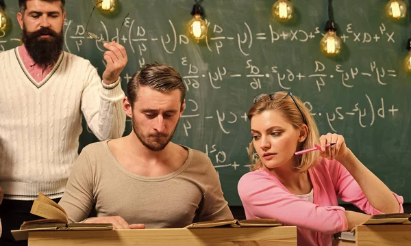 Concepto de educación universitaria. Estudiantes, compañeros de grupo hablando, pidiendo consejo o haciendo trampa mientras el profesor los observa. Profesor barbudo, conferenciante, profesor observando a los estudiantes durante la prueba, examen, lección . — Foto de Stock