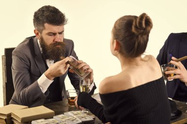 Şirket yasadışı iş yapan. Erkek ve kadın para yığınları ile masada oturuyordu. Yasadışı anlaşma kavramı. Yasadışı tartışırken işadamları yudumlarken anlaşma ve sigara, arka plan beyaz.