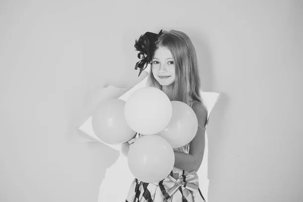 Маленькая девочка с воздушными шарами на розовом фоне студии — стоковое фото