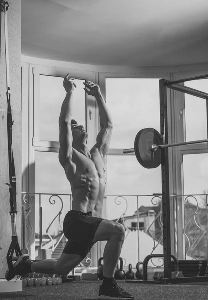 Sport and gym concept. Man with torso, muscular macho does exercise with trx loops, window on background. Sportsman, athlete looks attractive. Man with nude torso in gym enjoy training, trx. — Stock Photo, Image