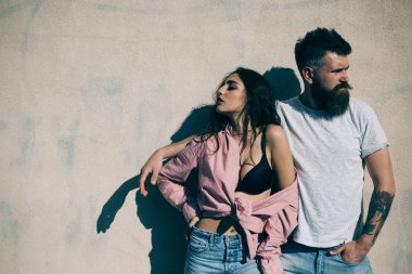 Sakallı adam kız arkadaşı tarafından omuz tutarak. Uzaklaşmış çift farklı yönlere, ilişki sorunları. Acımasız adam ve beyaz duvar üzerinden küstah kız yan görünüm.