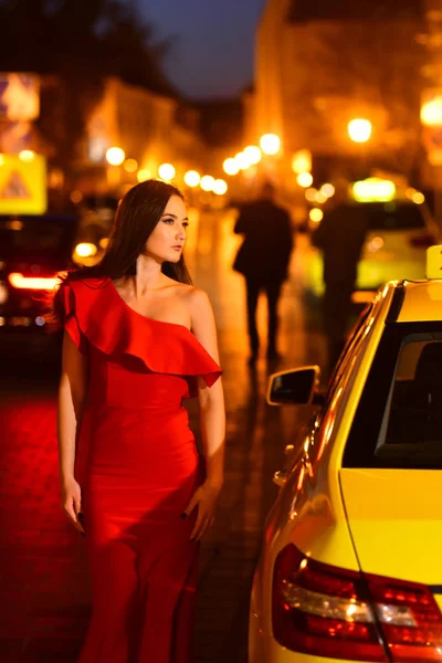 Night city with princess in celebrity style. night city with woman in red dress wait for taxi