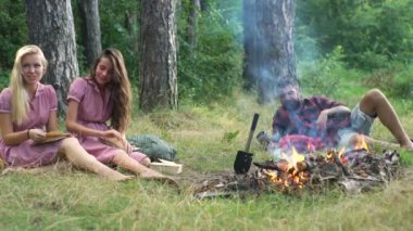 Müzik çalma ve doğada şenlik ateşi zevk mutlu arkadaşlar. Gençler eğleniyor orman. Ormanda oturan arkadaşlar bir kamp ateşi daire