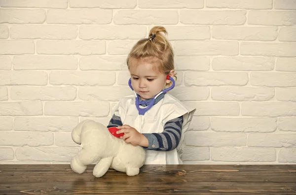 Концепция счастья детей детского детства. Детские игры доктор с плюшевым мишкой на белой стене — стоковое фото