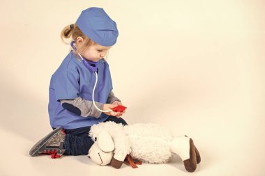 Mutlu bir çocukluk eğleniyor. Doktor veteriner oyuncak hayvan ile oynarken üniforma içinde küçük çocuk