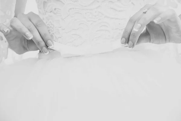 Руки невесты девушки держать белый лук на свадебное платье — стоковое фото