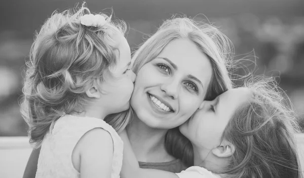 Little girl face portrait in your advertisnent. Daughters kiss mother on natural landscape — Stock Photo, Image