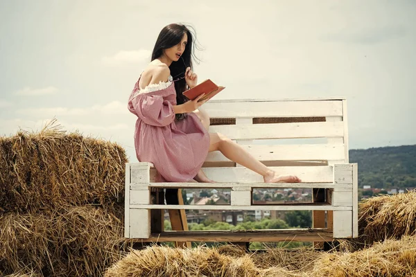 Чувственная женщина. Девушка сидит на деревянной скамейке на сене — стоковое фото
