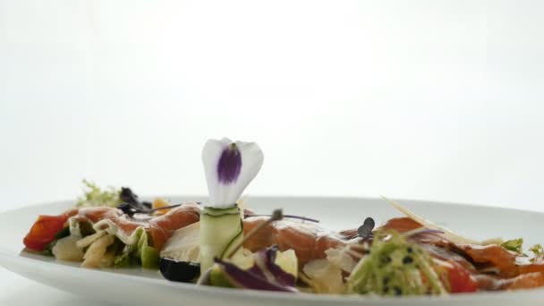 Deliciosos rollos de pescado rojo o salmón con caviar de naranja gelatina y ensalada verde mezclados en un plato sobre fondo borroso y colorido. Gastronomía molecular moderna . — Vídeos de Stock