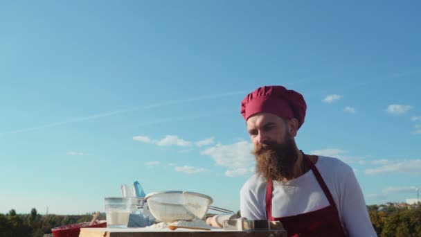 Bebaarde baker. Baker buiten koken. Eco bakkerij. Baker een vers brood bakken — Stockvideo