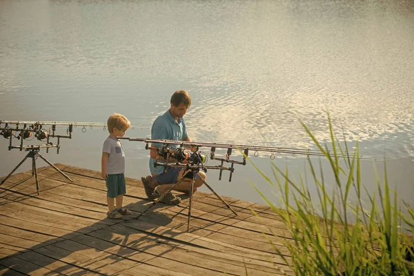 Dad helps son catch fish with fishing rod — Stock Photo, Image