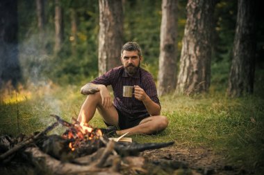 Hipster hiker kupa ile rahatla ormandaki şenlik ateşi