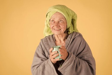 Emeklilik ve emeklilik. Sabah kahve içme kadın. Havlu türban Kupası ile yaşlı bayan. Ferahlık ve enerji.