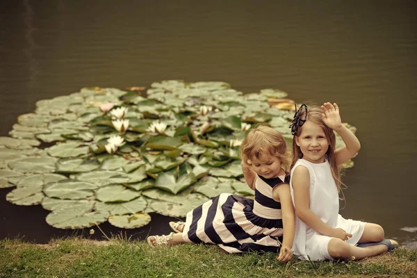 Bambini che giocano - gioco felice. Ragazza onda mano allo stagno con fiori di ninfee — Foto Stock