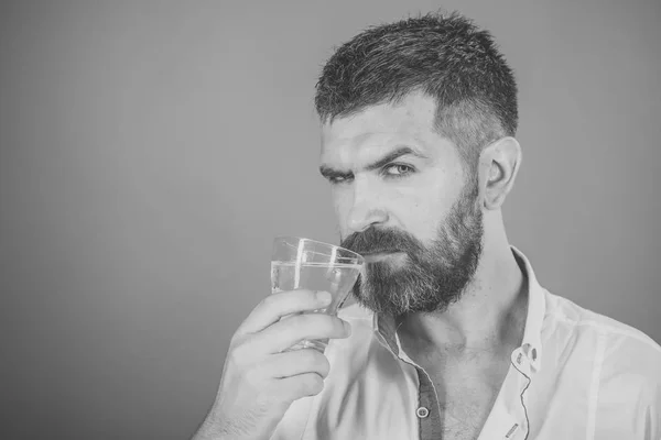 Mannen gezicht huidverzorging. Portret mannen gezicht in uw advertisnent. Man met lange baard houden waterglas op rode achtergrond. — Stockfoto