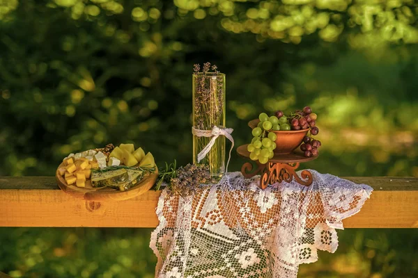 Bodegón de uvas, queso, lavanda, jarrón sobre mantel blanco — Foto de Stock