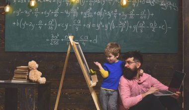 Okulda öğretmen ile öğrenci. Baba ve oğul yeni bilgi ve becerileri eğitim. Çocuk Baba boynundan oturan sarılma iken kara tahta işaret