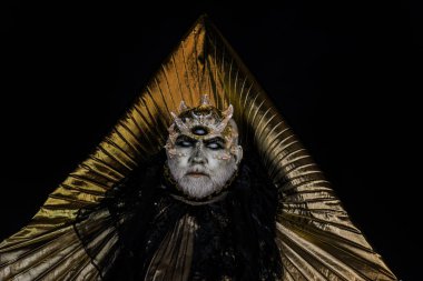 Ürkütücü deniz canavarı dikenler, Yüce Tanrı onun alanda dinlenme dragon cilt. Üçgen altın yakalı siyah arka plan üzerine izole koyu kıyafeti yabancı veya sürüngen makyajlı sakallı adam