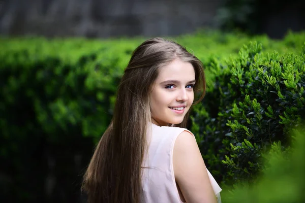 Portrait of beautiful woman against summer green park — Stock Photo, Image