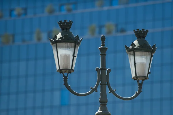 Lamp post on glass facade. Street lamp on sunny day. Street lighting of outdoor. Vintage or retro style and design. Architecture and design