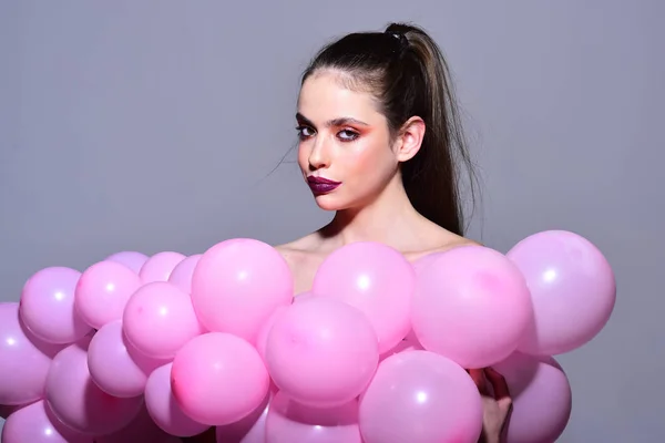 Fille rétro avec un maquillage élégant et les cheveux. Femme de mode avec de nombreux ballons à air rose. Décor d'anniversaire et célébration. Balloon party sur fond de studio gris. fille rêvant dans punchy pastels tendance — Photo