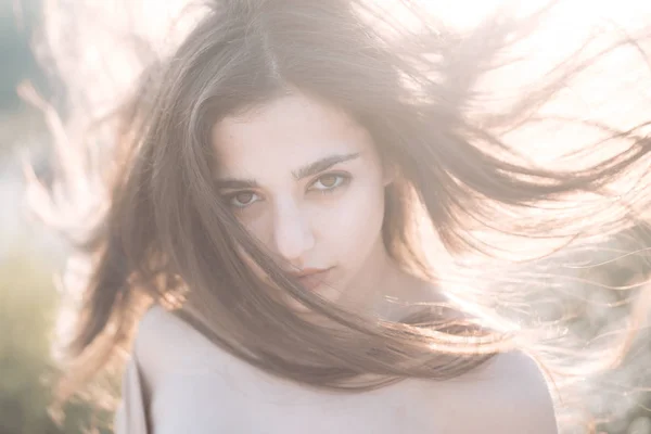 Menina com ombros nus desfrutar de seu cabelo acenando pelo vento. Concepção de cuidados com o cabelo.Mulher no rosto calmo desfrutar de dia ensolarado e ventoso, natureza no fundo, desfocado. Senhora parece atraente com acenando cabelo longo . — Fotografia de Stock