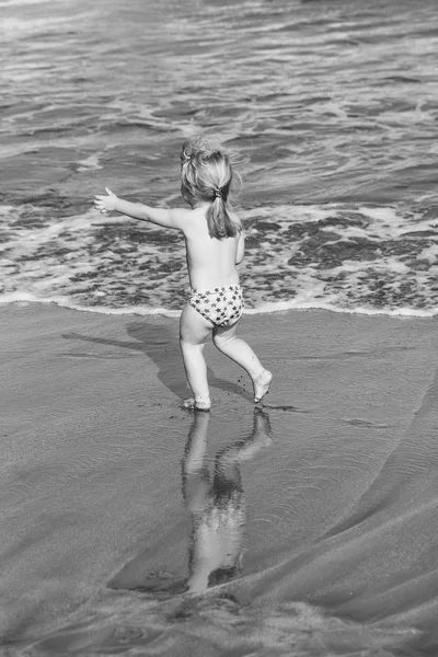 Juego de niños. Lindo bebé alegre corre sobre arena mojada a lo largo del mar — Foto de Stock