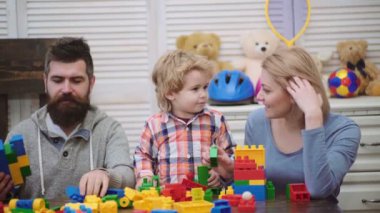 Genç aile oyun odası. Aile kavramı seviyorum. Anne, baba ve çocuk oyuncakları ile dışarı plastik blokları inşa. Anne ve oğlu gülümseyen, tuğla yapılar yapmak.