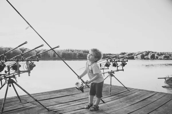 Концепция счастья детей детского детства. Рыжий ребенок с удочкой на деревянном пирсе — стоковое фото