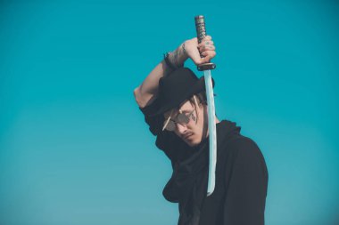 Kılıç üzerinde mavi gökyüzü ile metal bıçak tutan adam